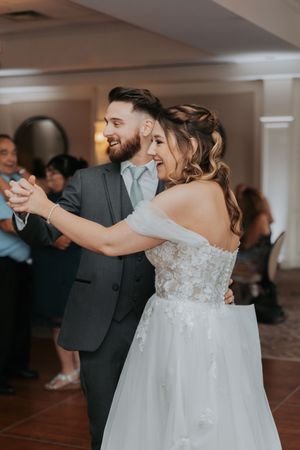 Wedding couple shares their first dance together surrounded by guests at their reception.