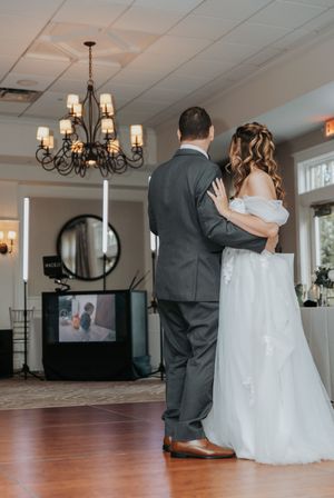 Wedding couple sharing first dance in elegant ballroom with chandelier lighting.