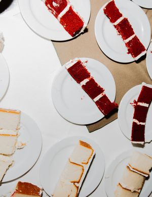 Multiple plates of red velvet wedding cake slices arranged on white dishes.