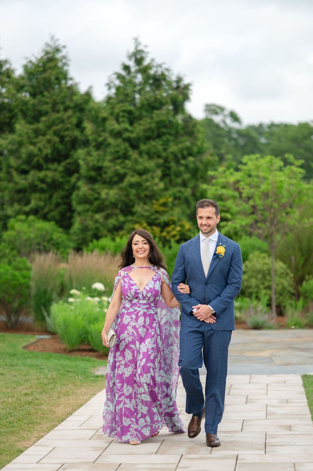 A groom and his mother walk down the aisle outdoors at the Lakehouse in Halifax, MA.