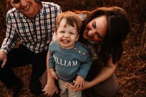 Overhead view of laughing parents with happy toddler William during fall family photo session.
