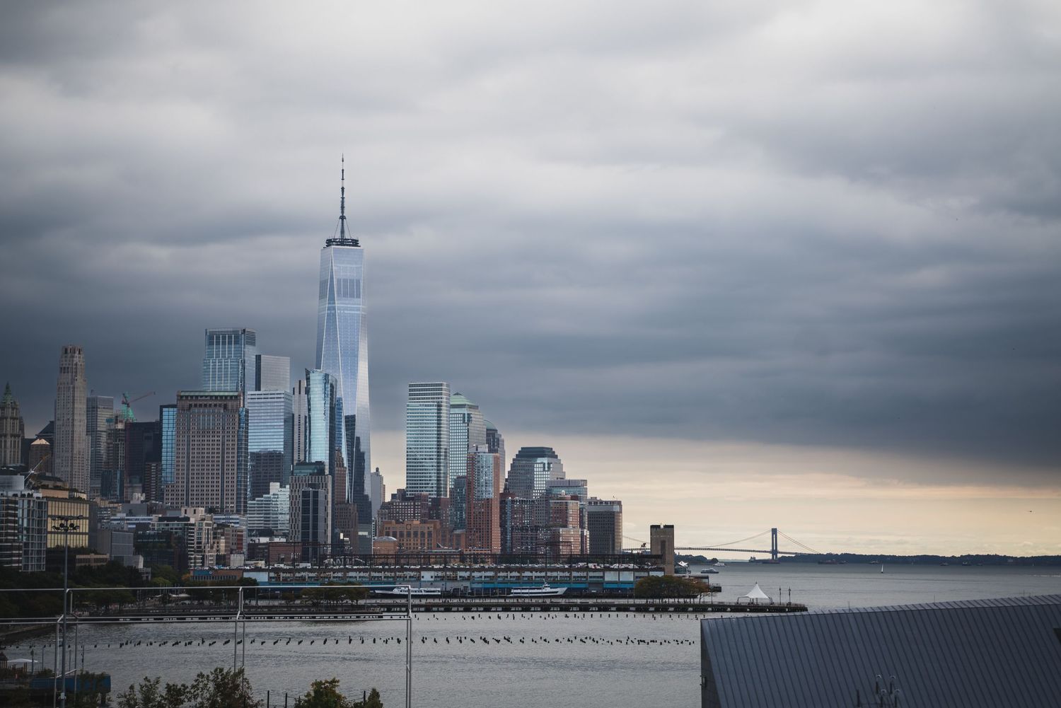 New York City skyline featuring One World Trade Center under dramatic stormy skies.