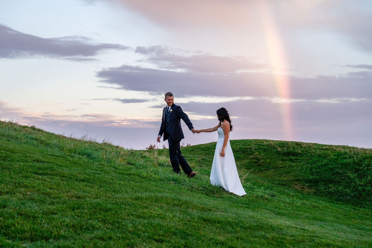 bride and groom walking under a rainbow. Maine wedding. Maine Wedding photographer.