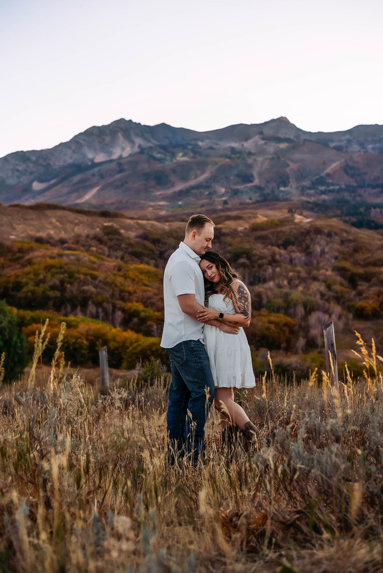 couple during a engagement photography session hugging each other with beautiful fall colors at snowbasin, utah