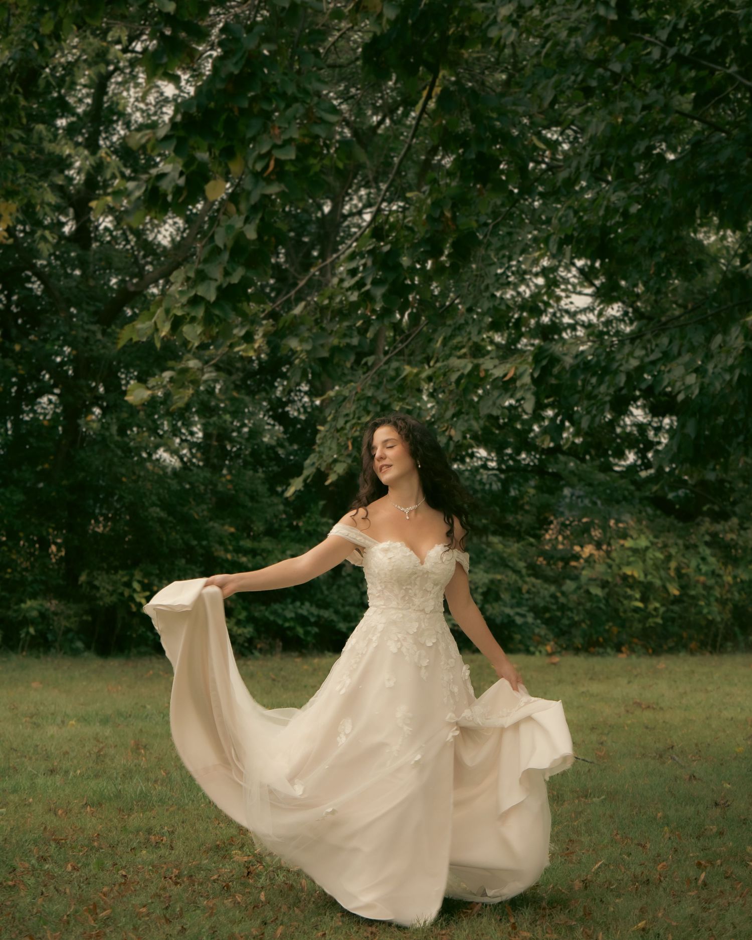 A bride twirls in a flowing white dress in an autumn field.