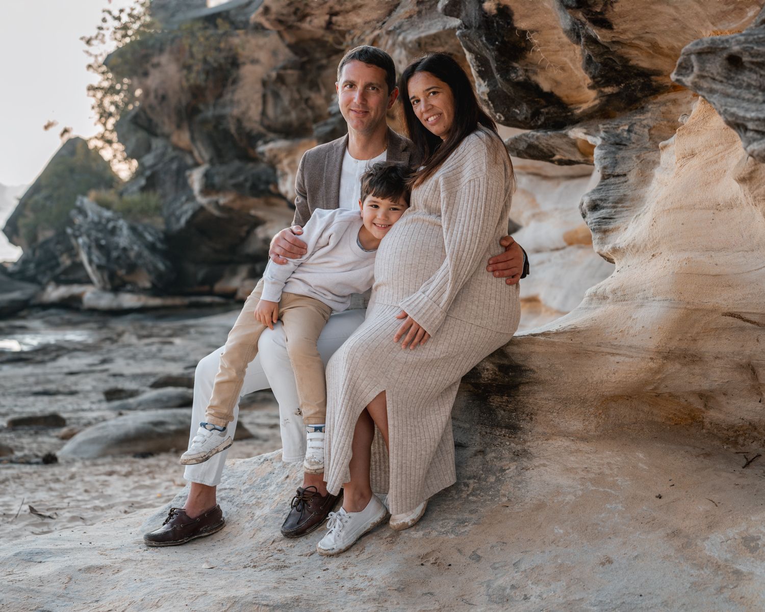A young boy lays on his mom's pregnant belly while his dad hugs her during a family photoshoot in Mosman, Sydney