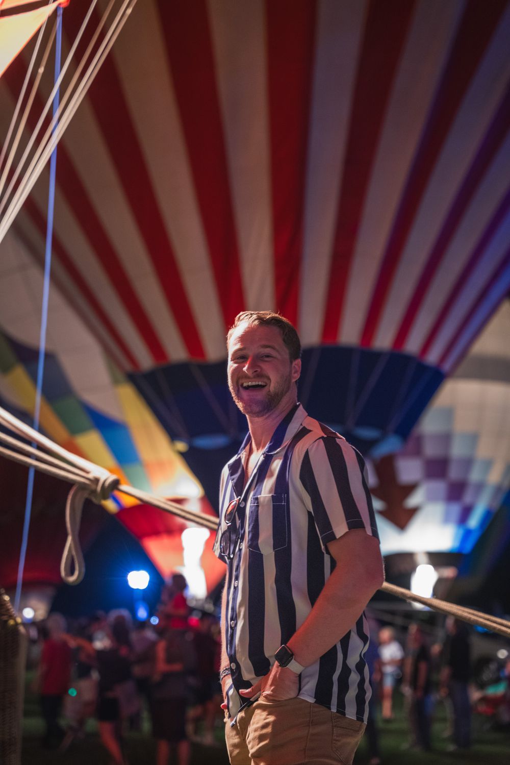 Person posing under carnival tent with red and white striped ceiling at night.