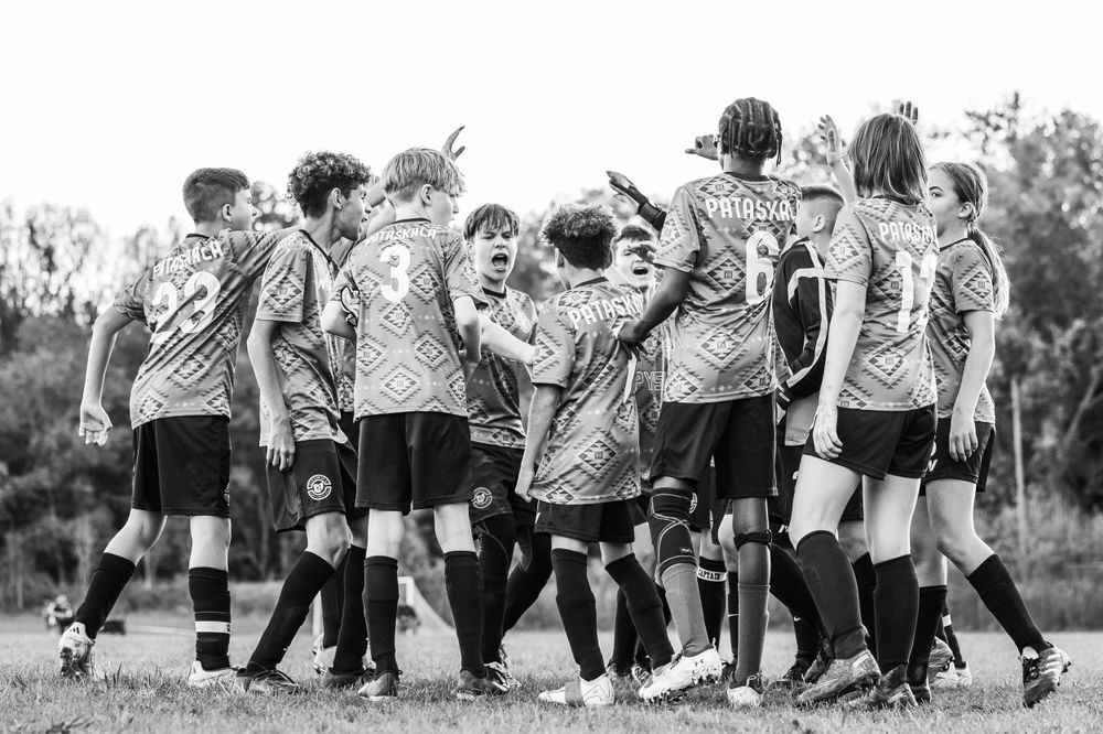 Soccer team huddles together in celebration wearing striped jerseys.