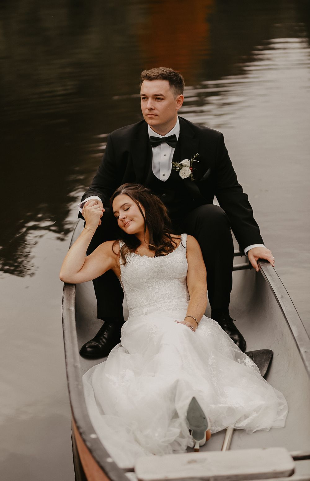 A romantic moment captured of newlyweds sitting in a rowboat on calm waters.