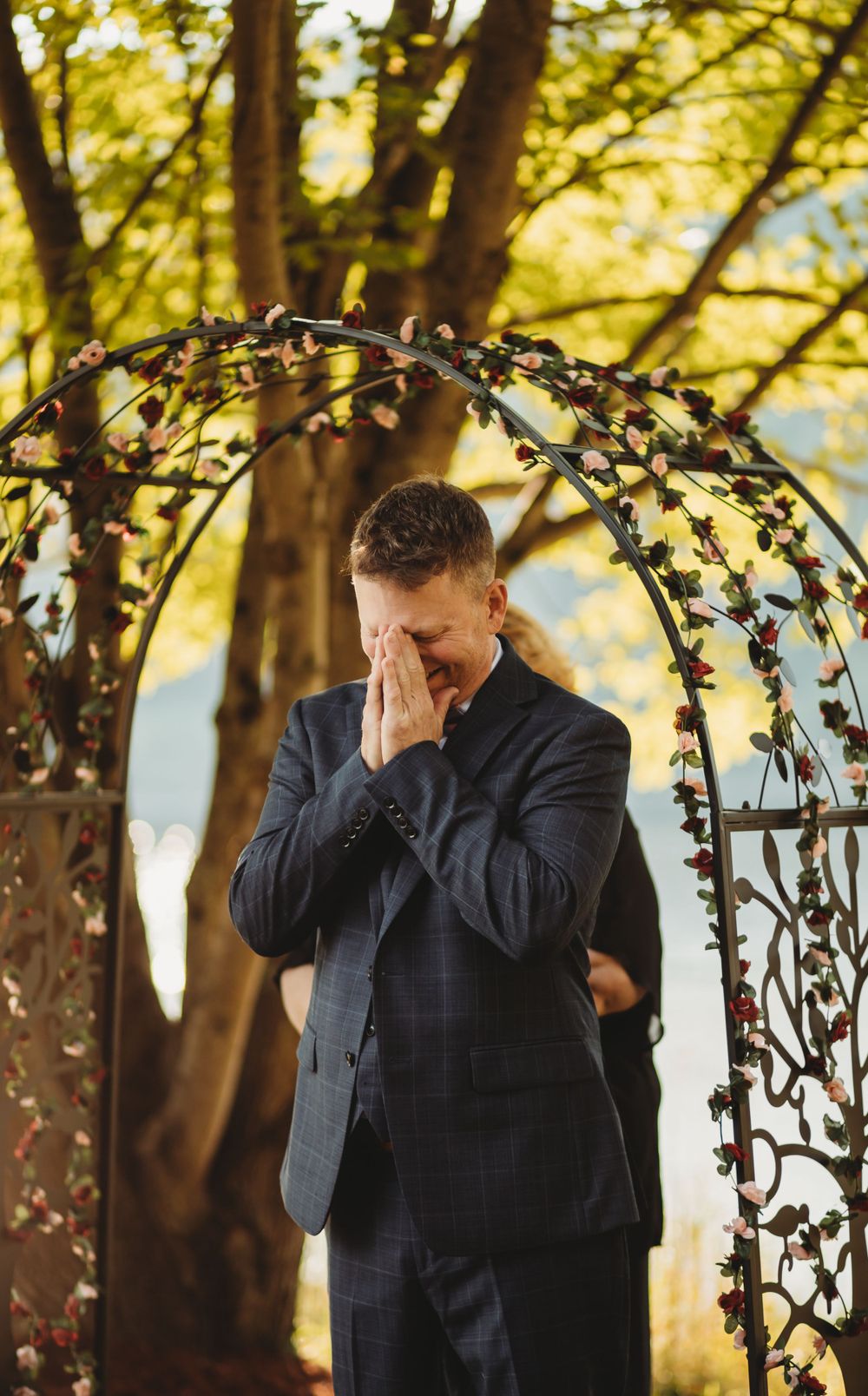 Emotional moment captured under floral arch in autumn setting.