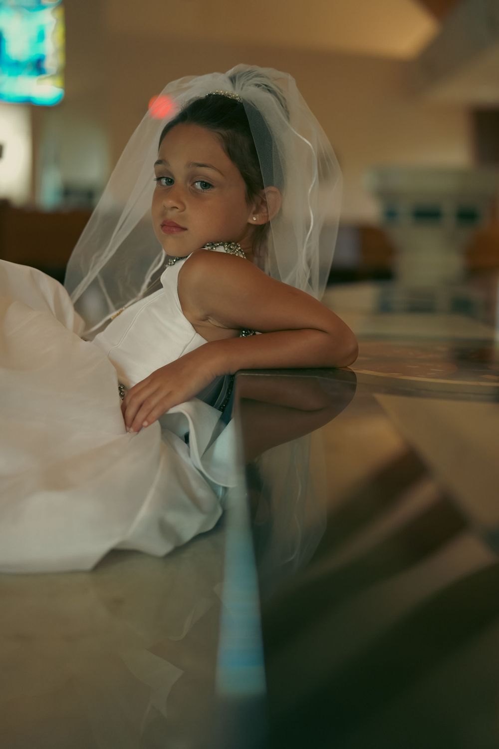 Close-up shots of a white wedding veil and dress in soft lighting.