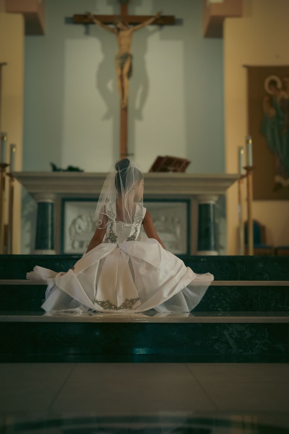 Wedding dress photographed in a church with a crucifix visible in the background.