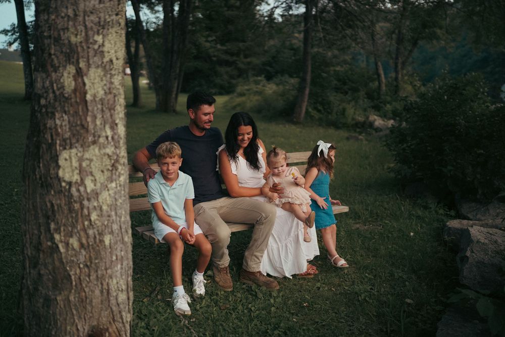 Family relaxing together outdoors near trees in natural setting.