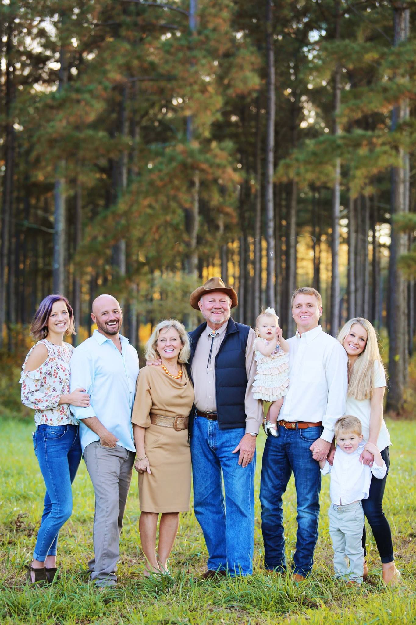 Multi-generational family poses together for portrait in front of pine forest.