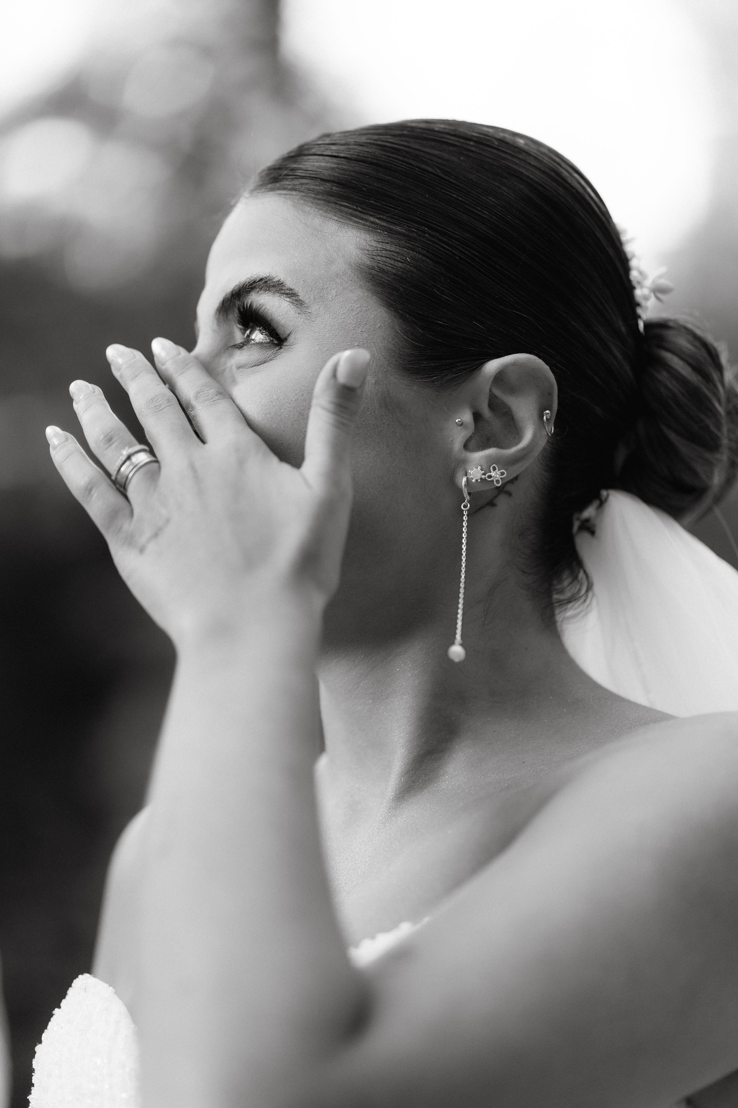 Black and white close-up shows elegant bridal jewelry and hairstyling.