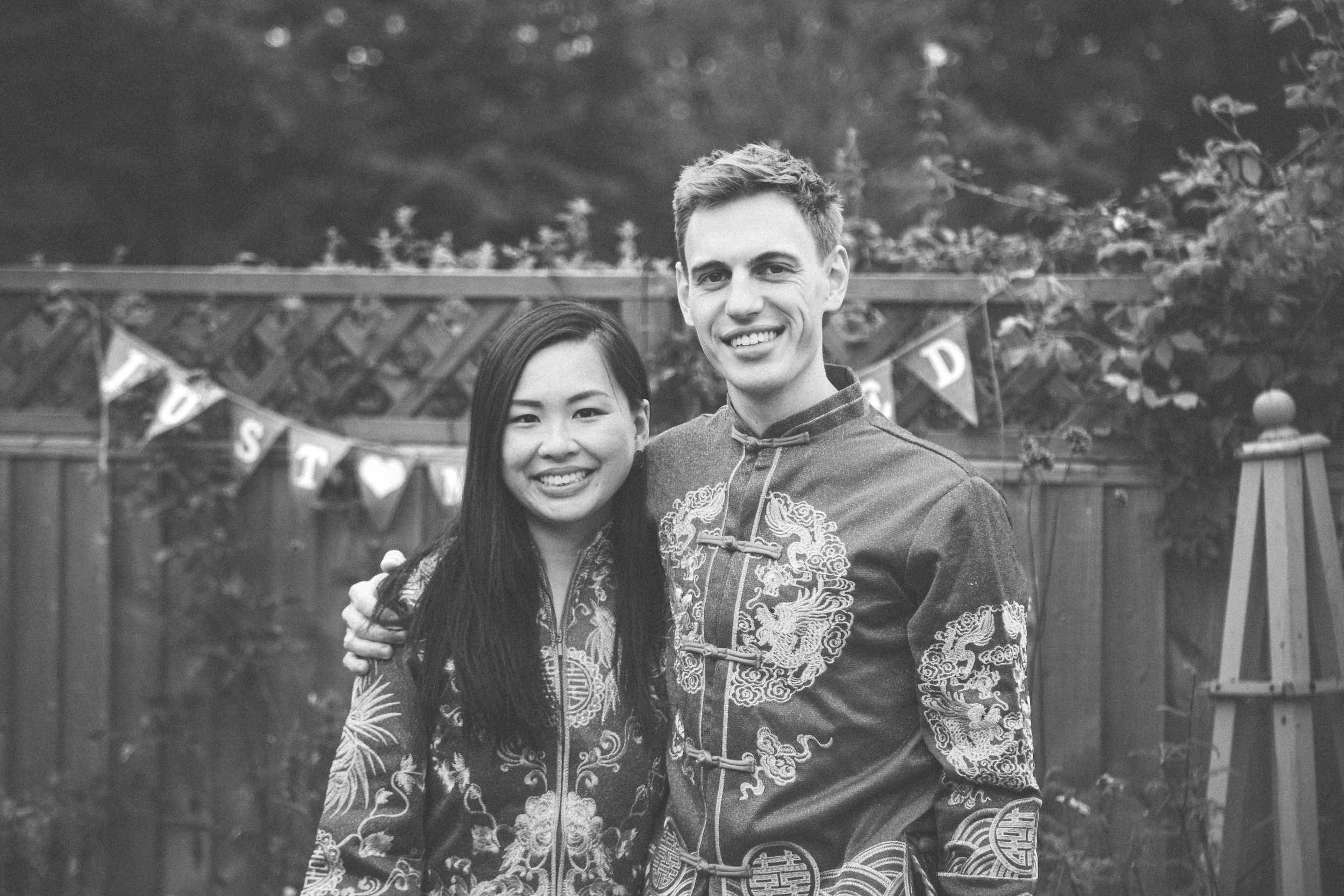 Couple in traditional red Chinese wedding outfits posing together in a garden.