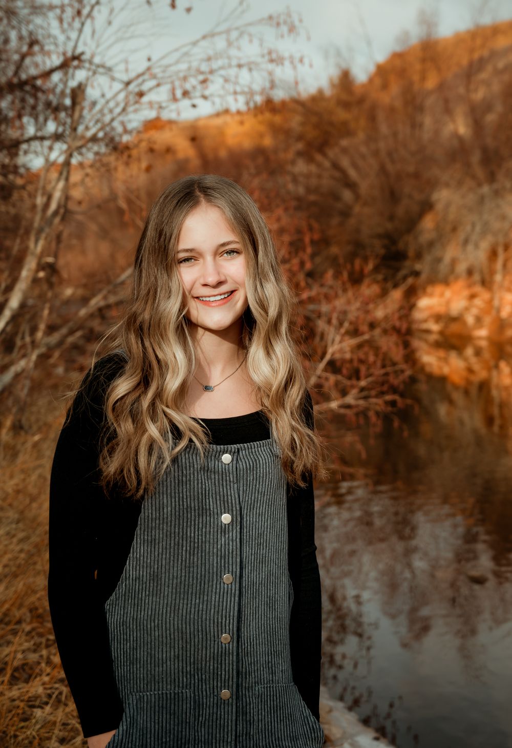 Outdoor portrait series against warm autumn colors and water reflections.