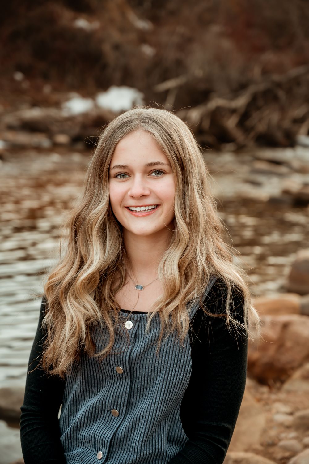 Natural light portraits by water with autumn colors and rocky shoreline.