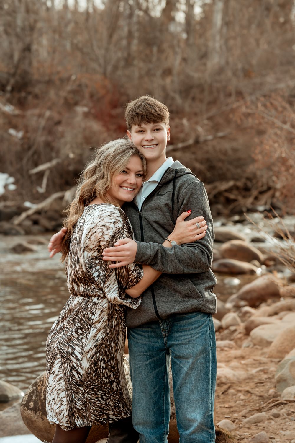 Candid family moments captured by rocky riverside in autumn setting.
