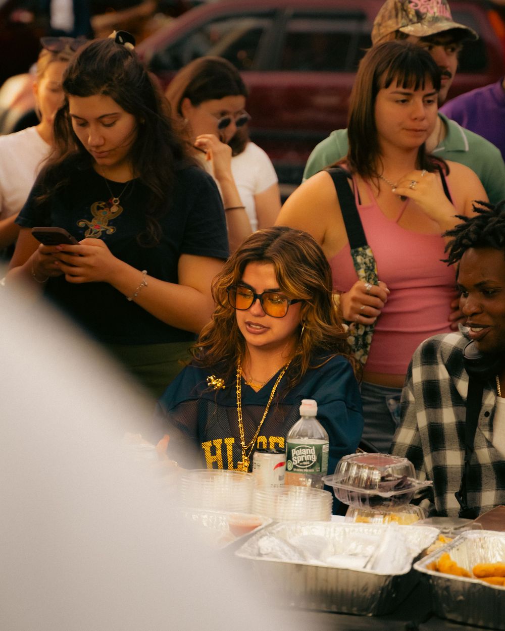 Students gather at a cafeteria table with takeout containers and drinks during a casual meal together.