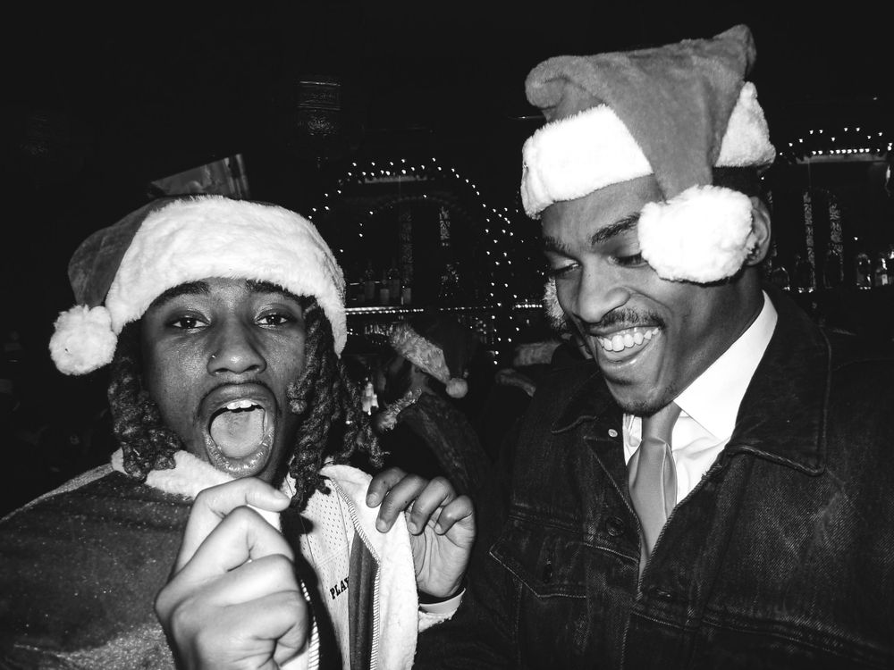 Vintage black and white photo of two people wearing Santa hats while smiling and having fun during the holiday season.