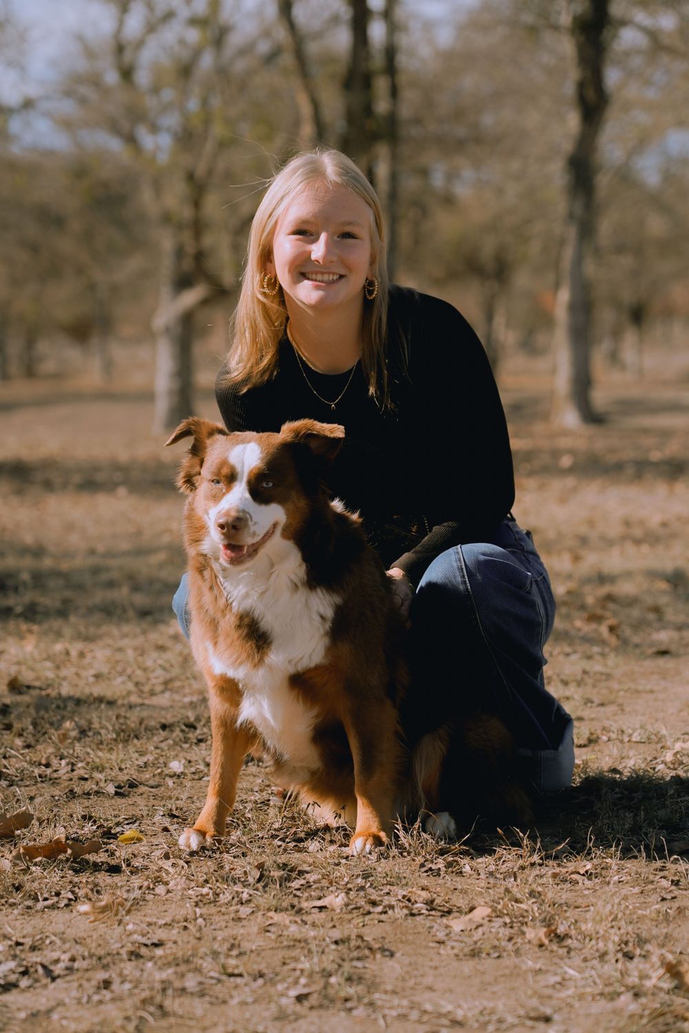 Person in black sweater poses with smiling brown and white border collie.