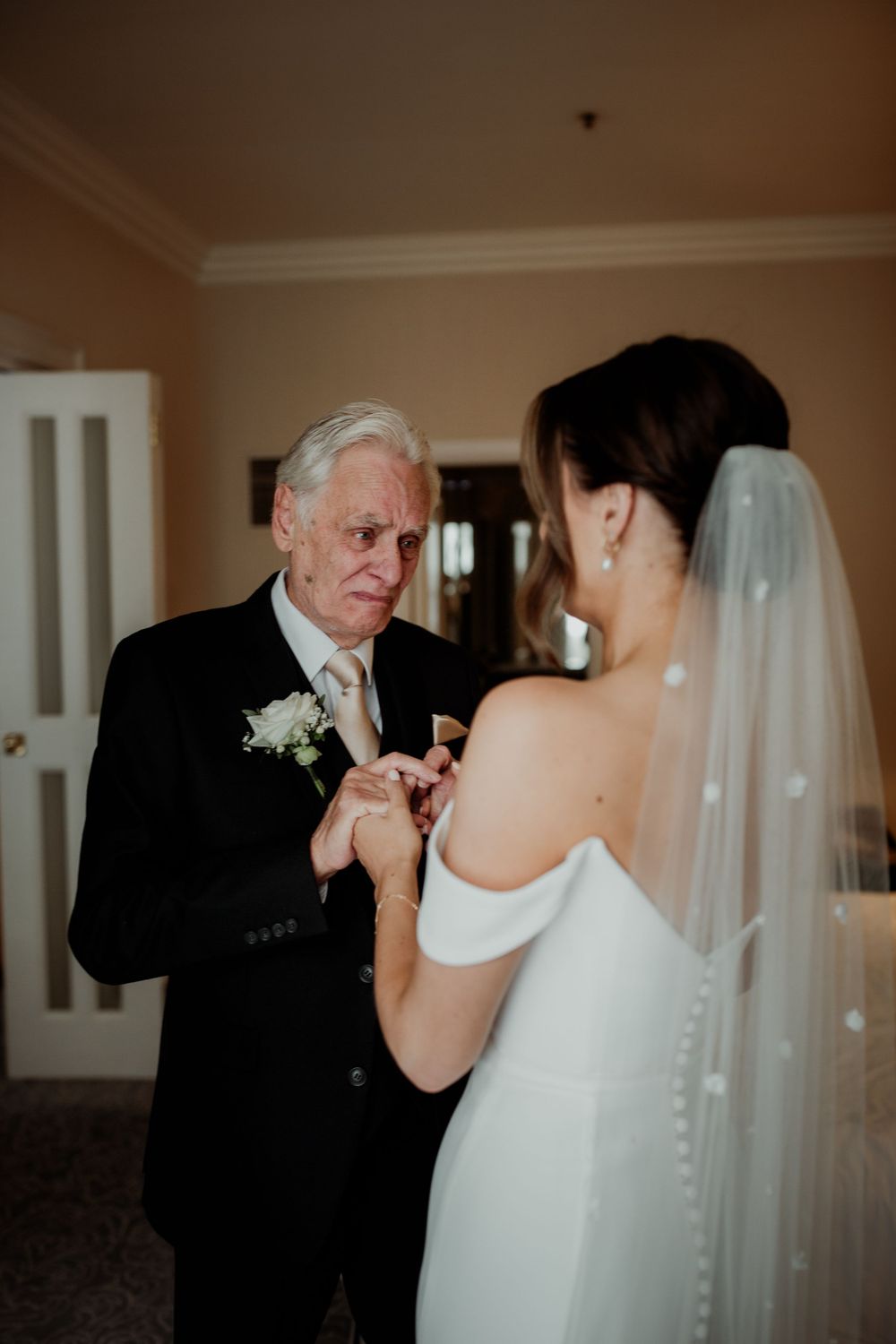 A formal wedding moment shows the bride in a white dress with flowing veil sharing a special moment indoors.