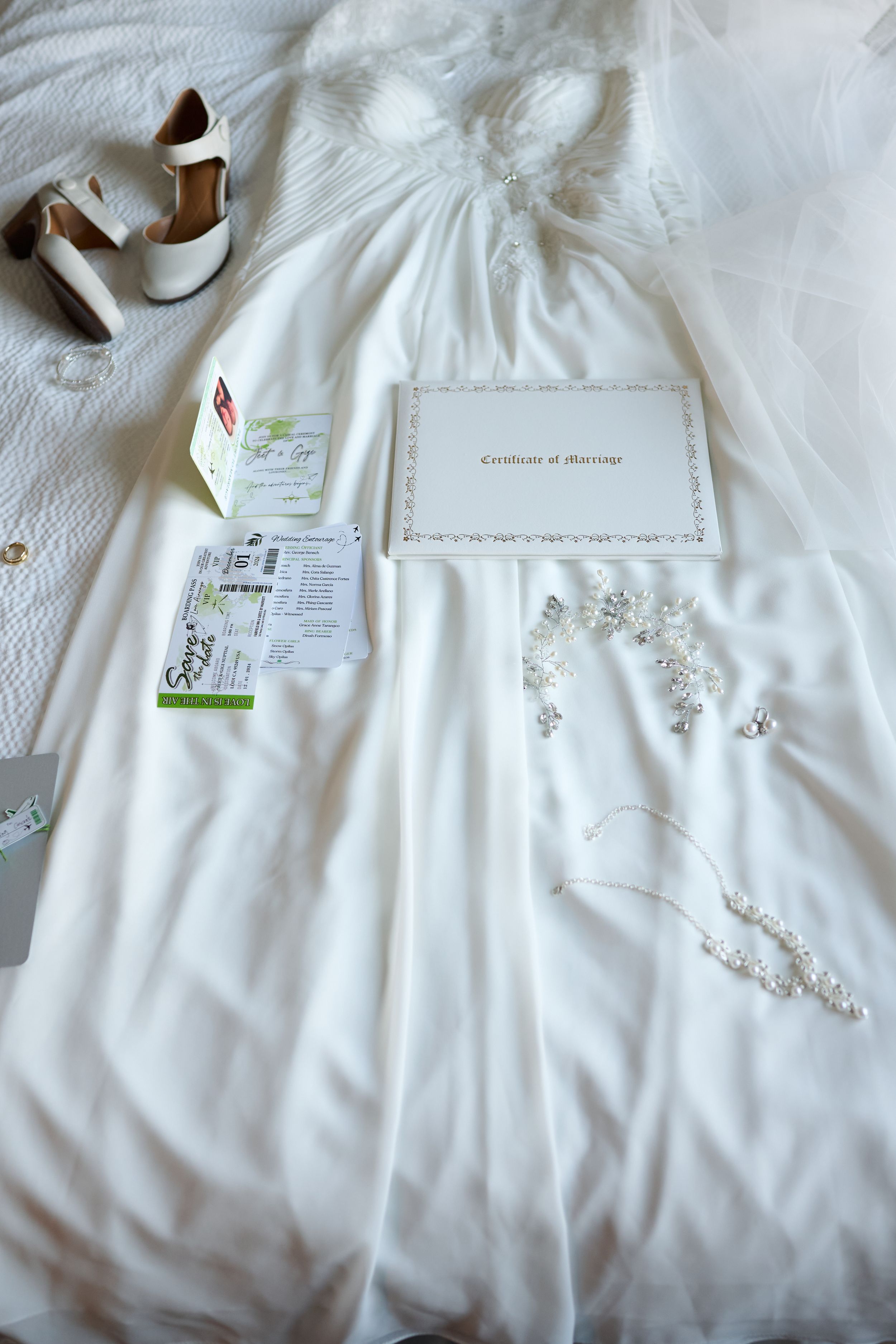 A white wedding dress laid flat with accessories including heels, invitation cards, and delicate floral decorations at Fairfield Inn & Suite