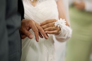 Close-up of newlyweds holding hands with wedding rings and delicate white lace dress detail at Fairfield Inn & Suites Lodi, California.