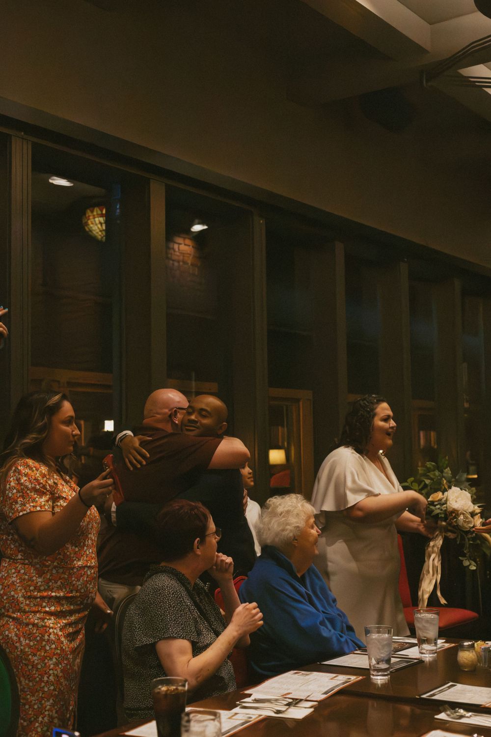 Evening social gathering with attendees seated at tables under warm lighting.