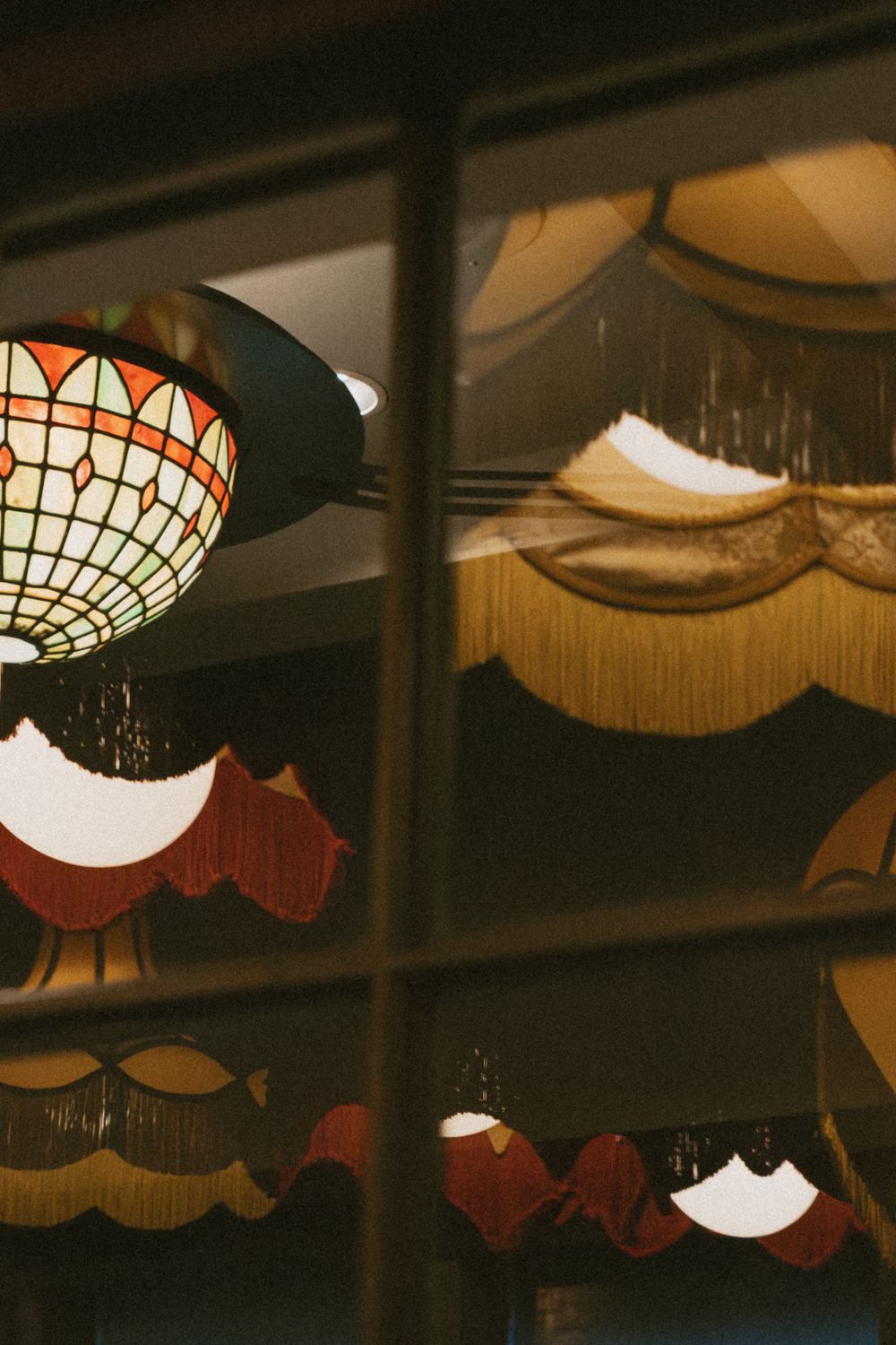 Decorative vintage-style pendant lamps with stained glass designs hanging from a dark ceiling.