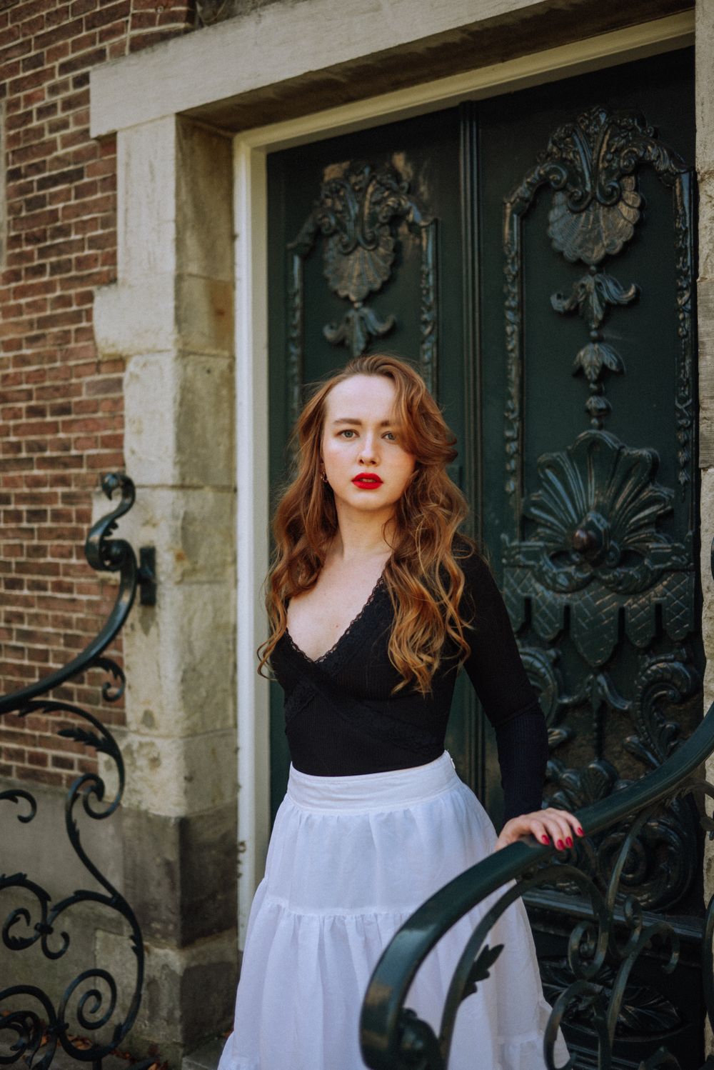 A sensual portrait of a red-haired woman with red lipstick in the gardens of the Rijksmuseum in Amsterdam.