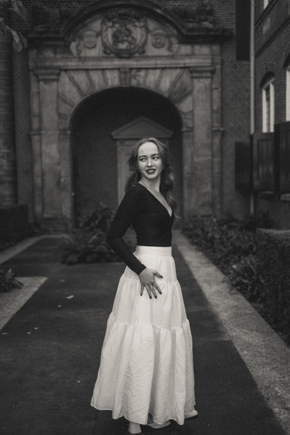 A figure twirls in a flowing white skirt against a backdrop of classical architecture.