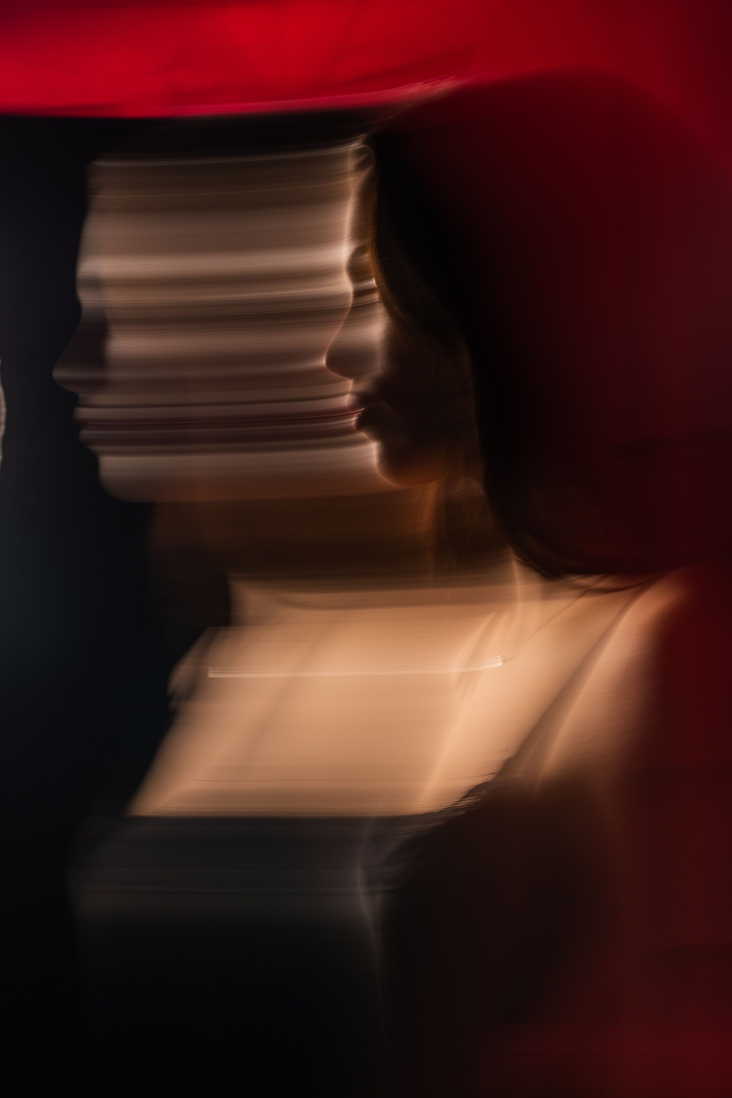 Abstract motion blur portrait of a woman with red and warm tones creating artistic effect.