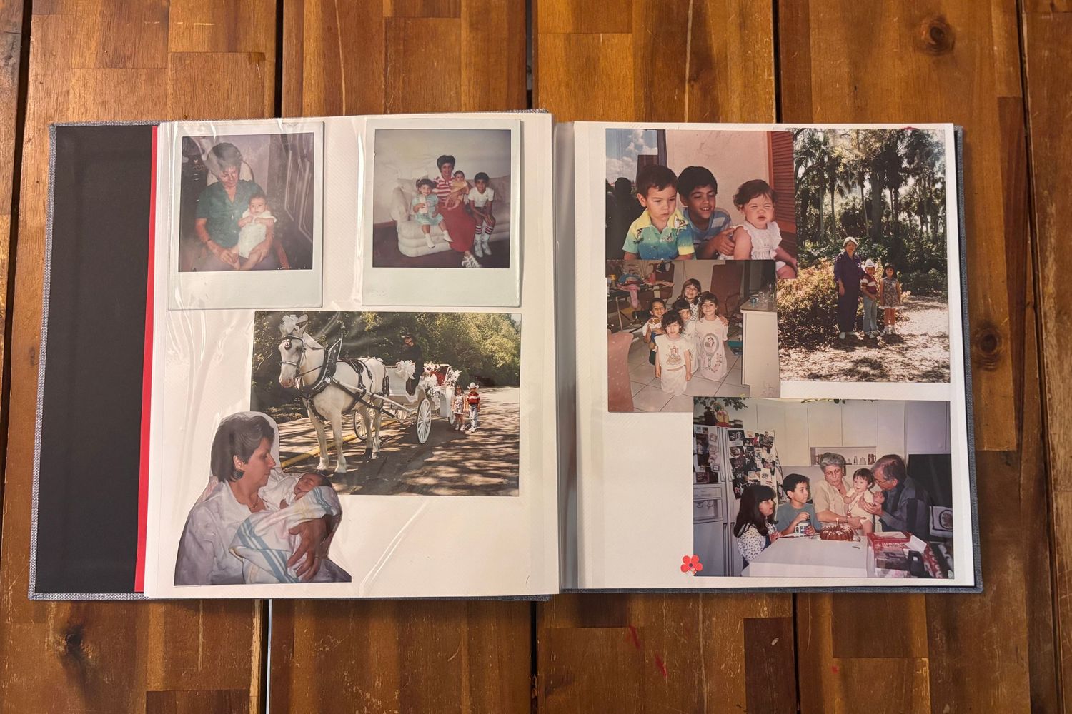 Open photo album displaying family photographs on wooden table surface.