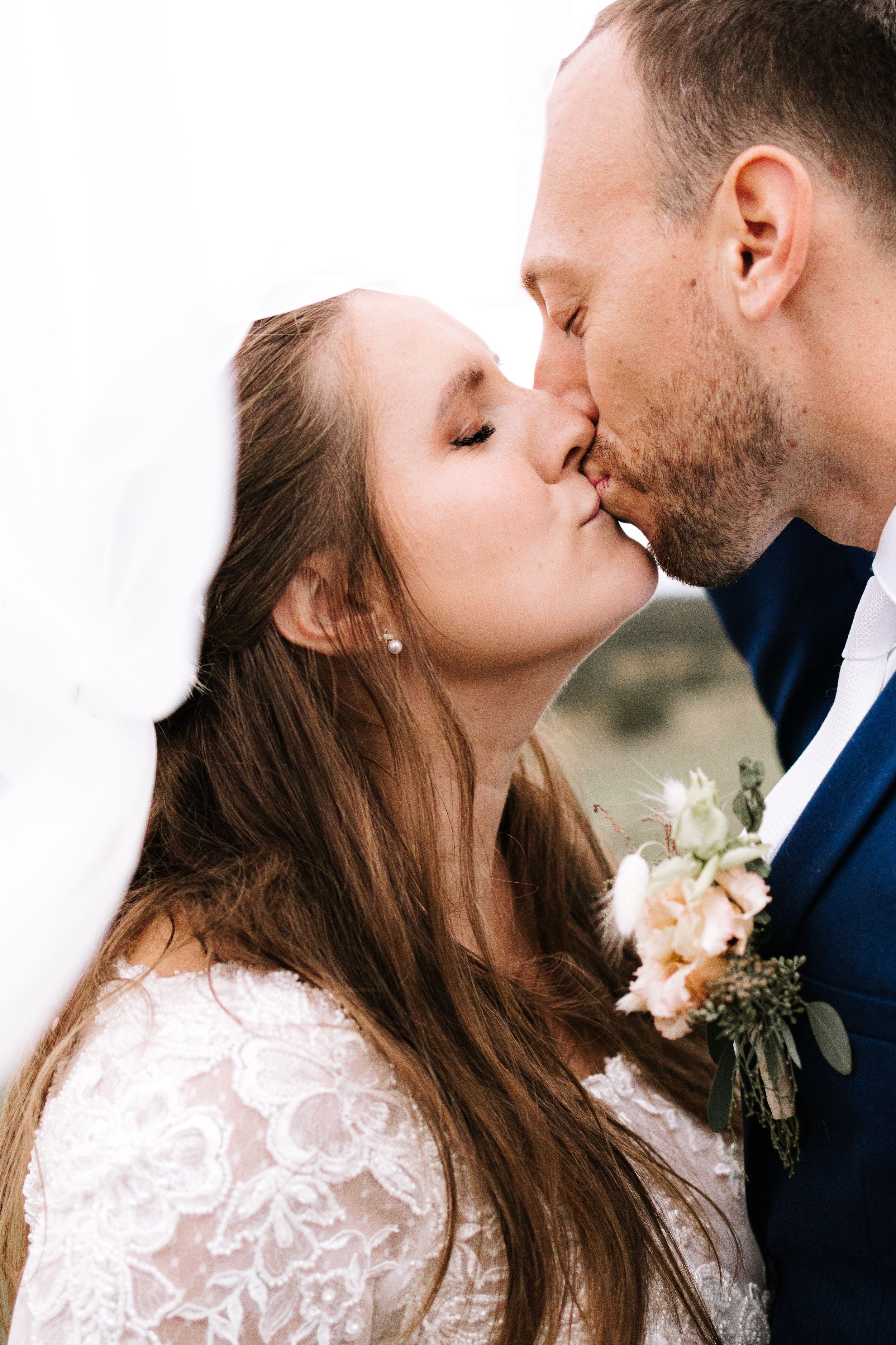 Detailní portrétní fotografie nevěsty a ženicha pod závojem