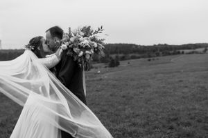 Něžný portrét nevěsty a ženicha s detailním záběrem na závoj