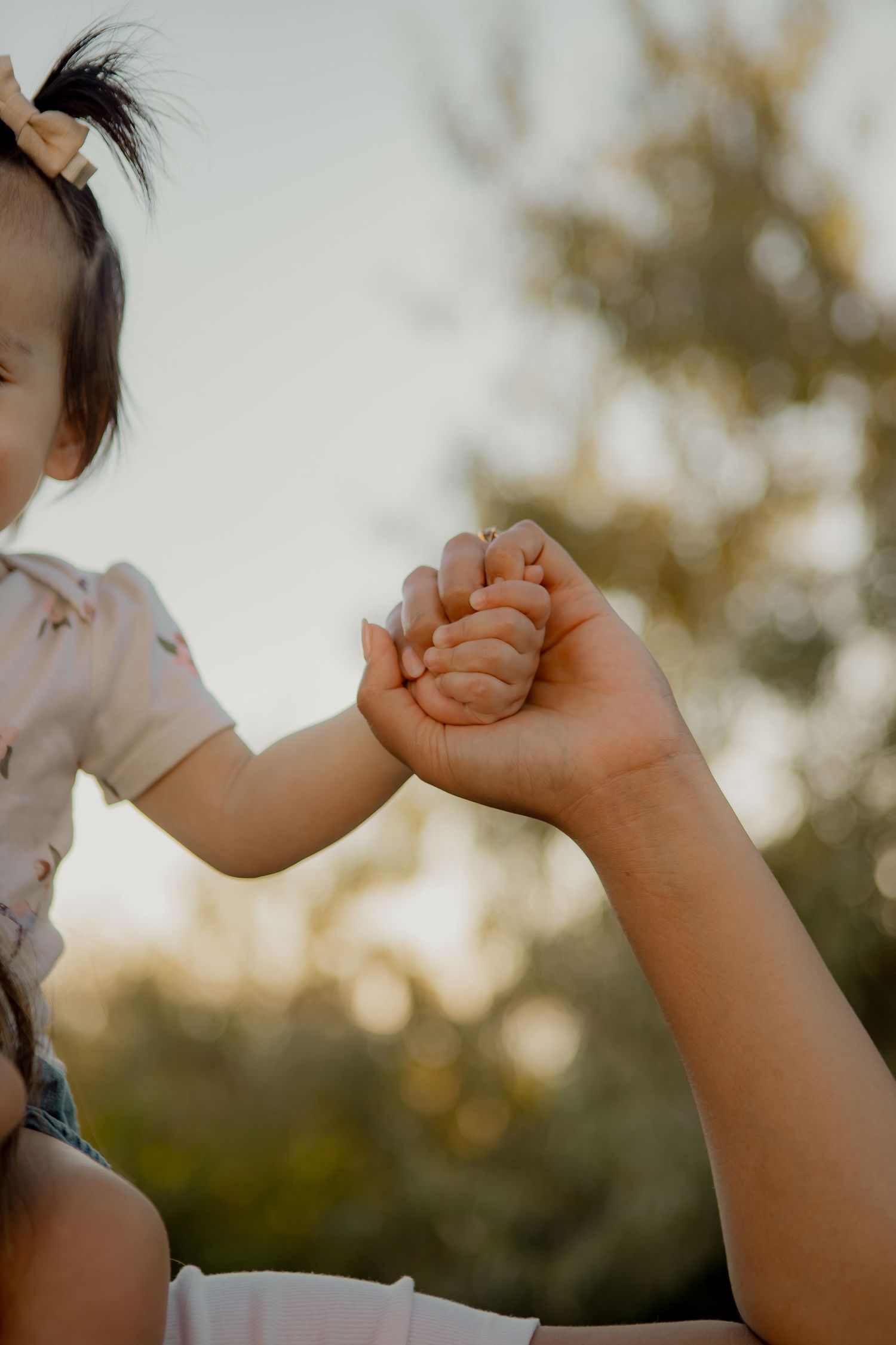Close-up of small hands clasping together against a sunset background.
