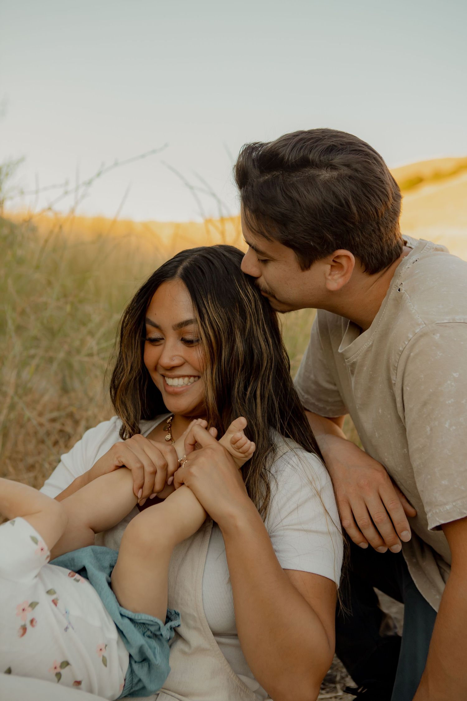 Intimate moment captured in golden hour light among tall grass.