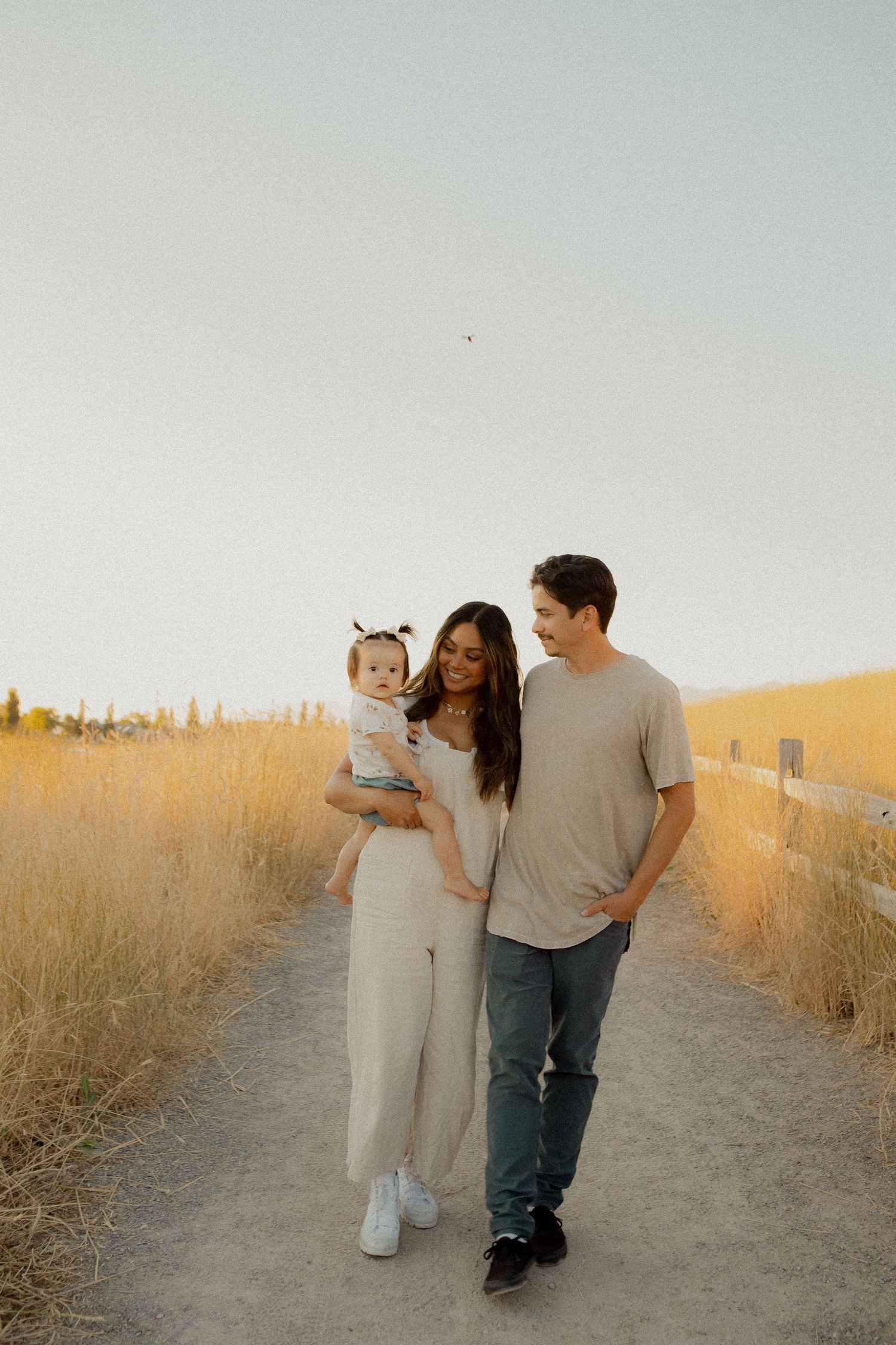 Family walking together on a dirt path during golden hour.