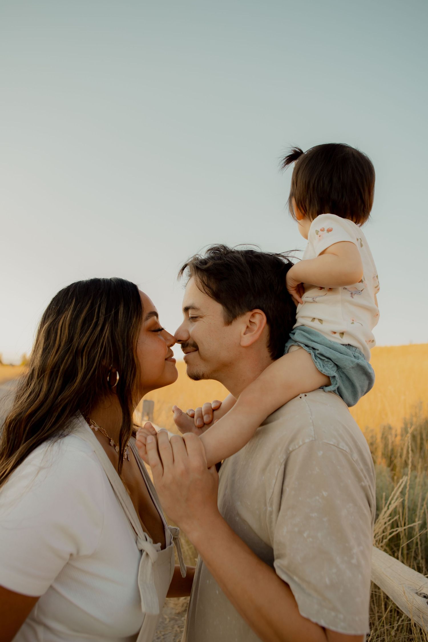 Tender family moment captured during sunset in a wheat field.