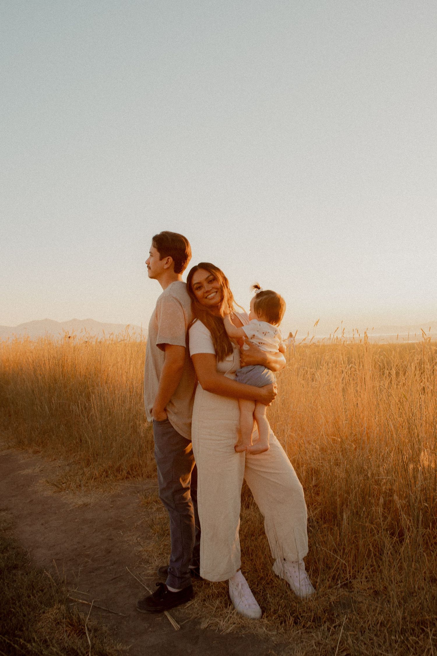 Family portrait at sunset with mountains and golden grass in the background.