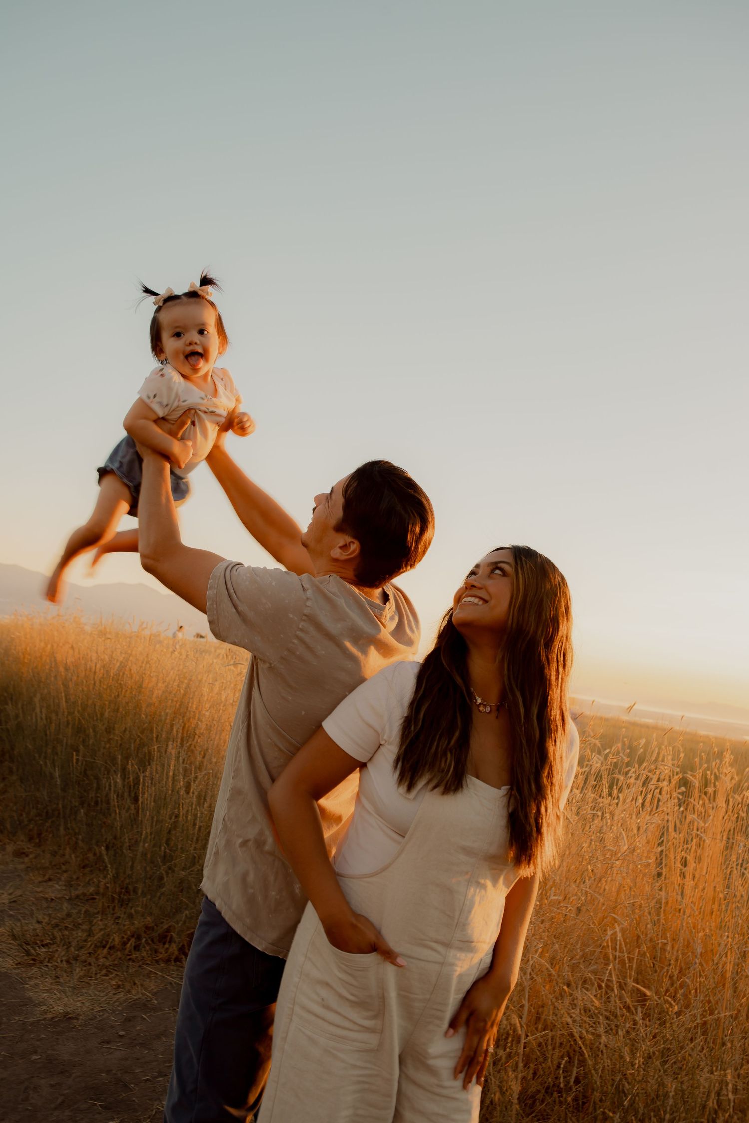 Playful family moment captured during sunset in a field of tall grass.
