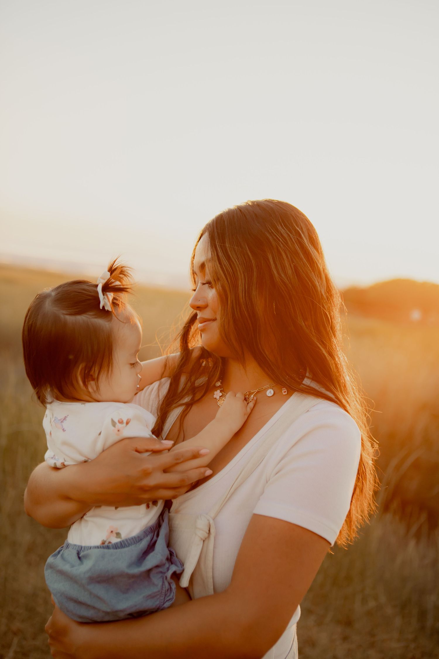 Mother and baby share an intimate moment together in warm sunset light.