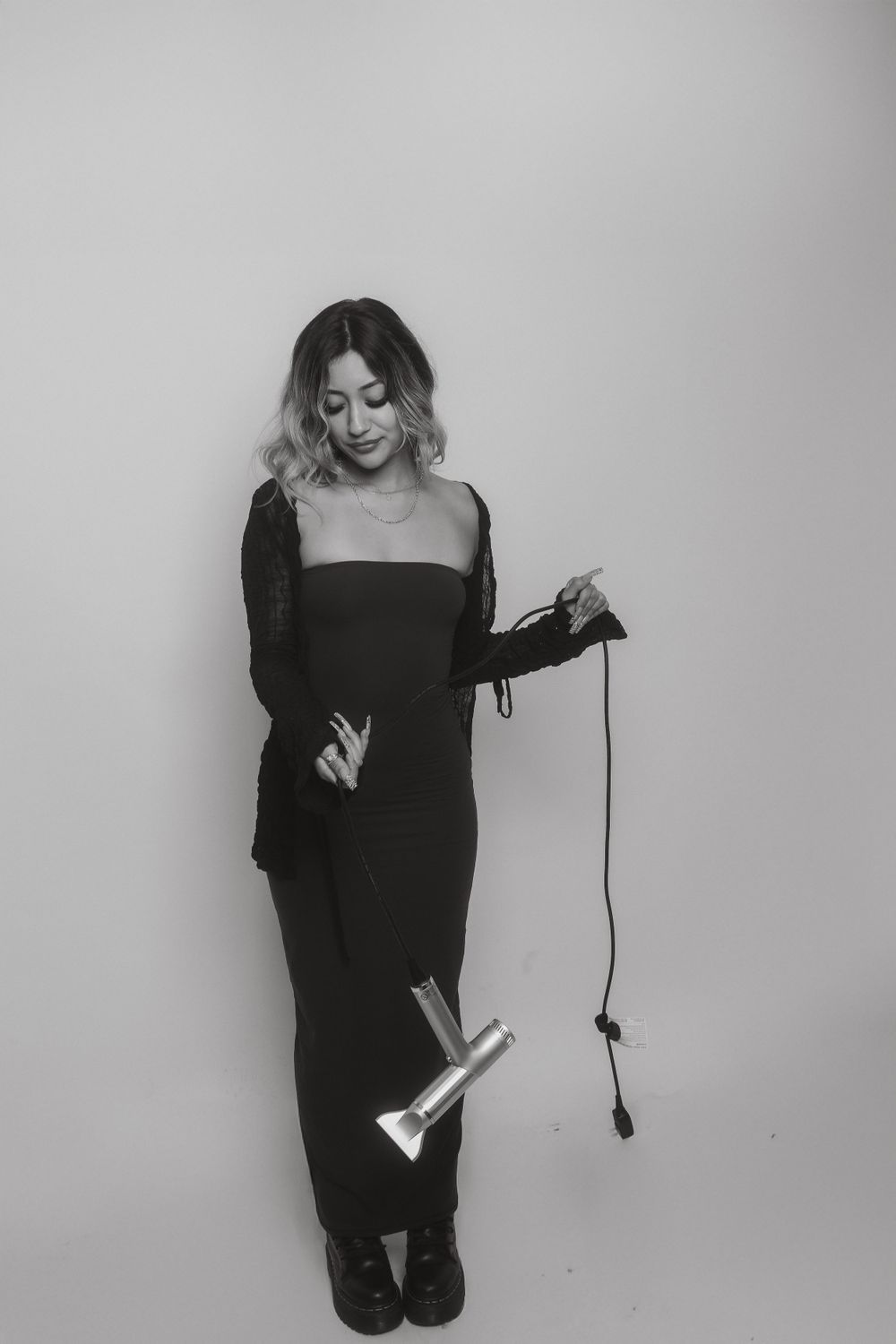 Studio portrait featuring hair styling tools and all-black attire.