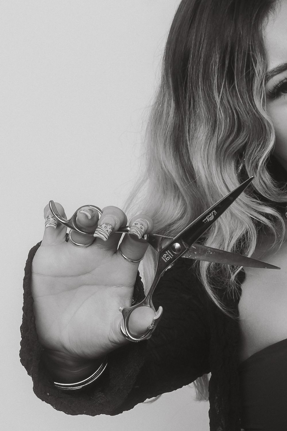Close-up view of hands holding professional hair cutting scissors in black and white.