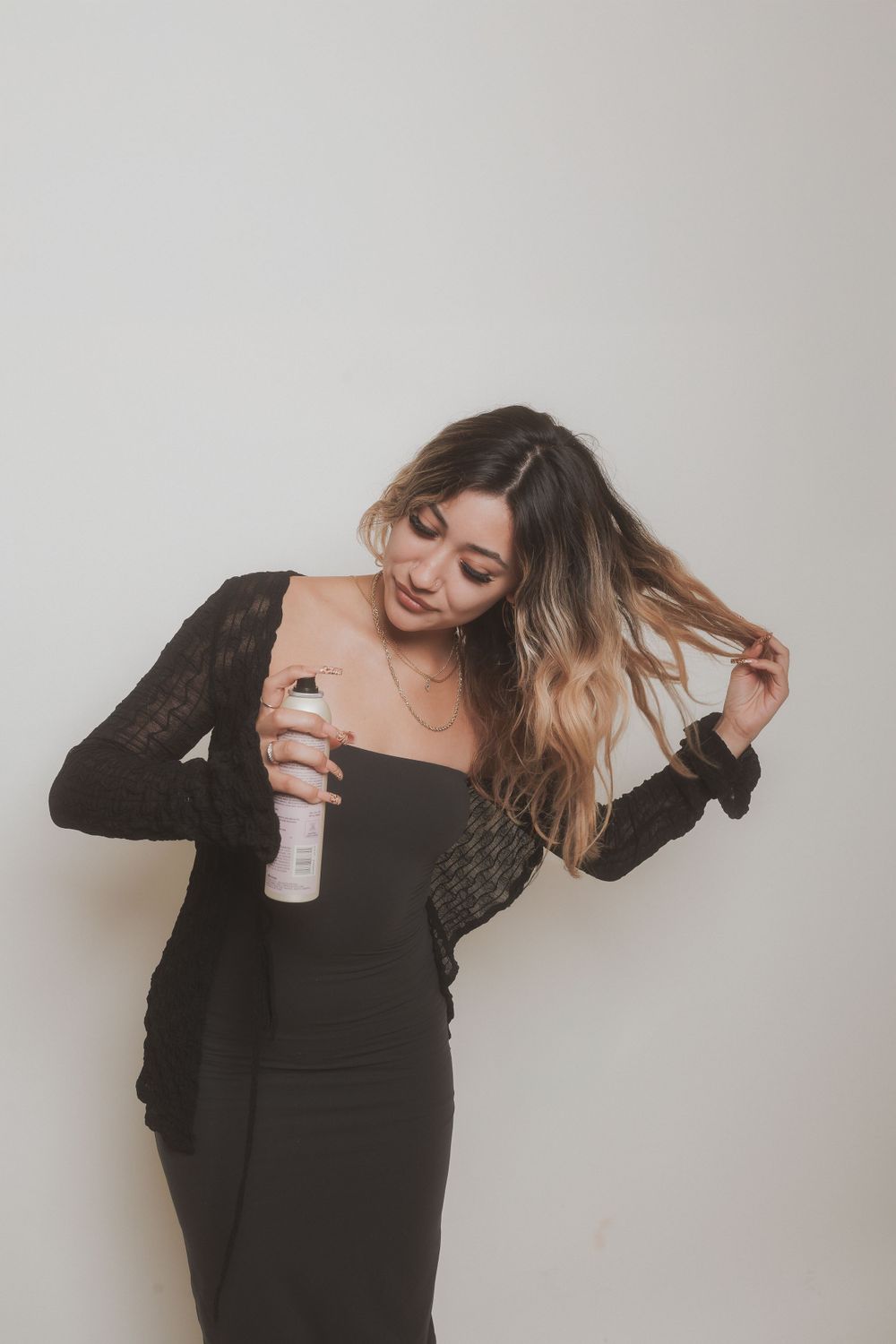 Candid moment showing someone in a black dress styling their hair with product.