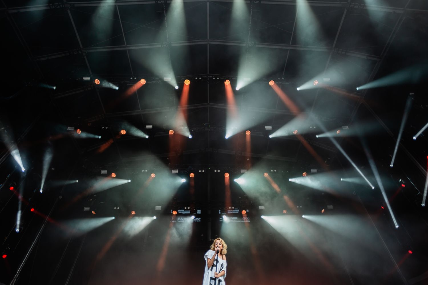 Concert stage with dramatic lighting effects and beams creating geometric patterns.