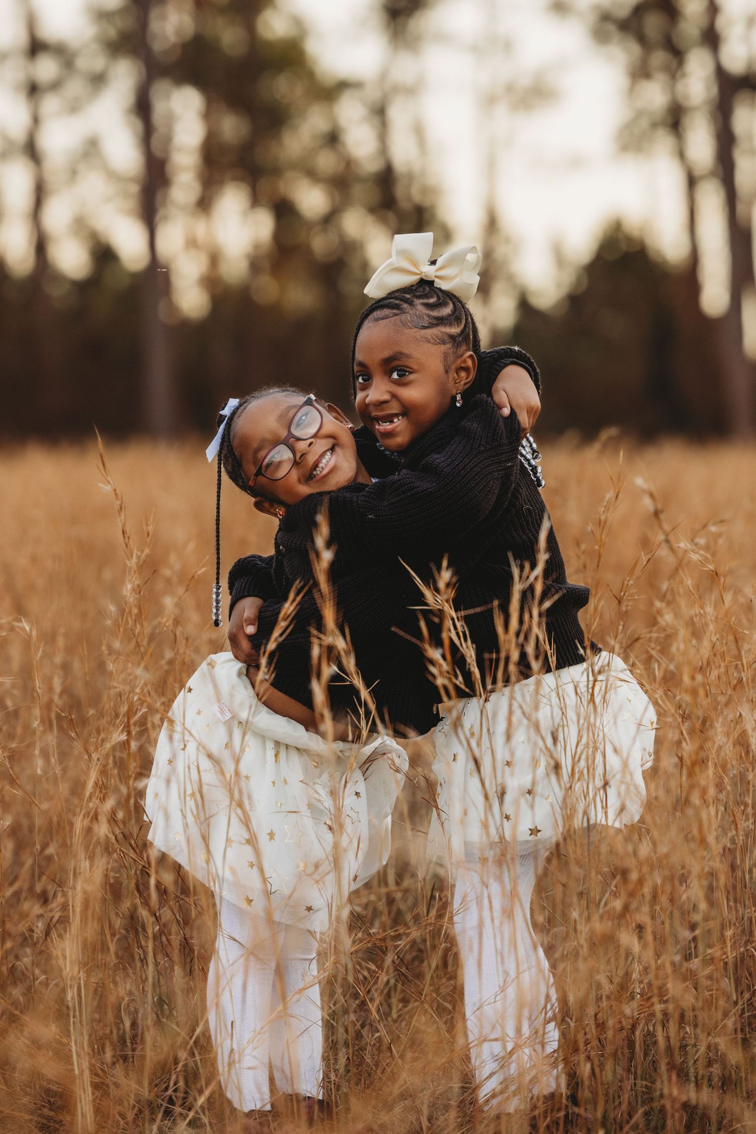 Joyful pair laughing together in a golden field of tall grass at sunset.