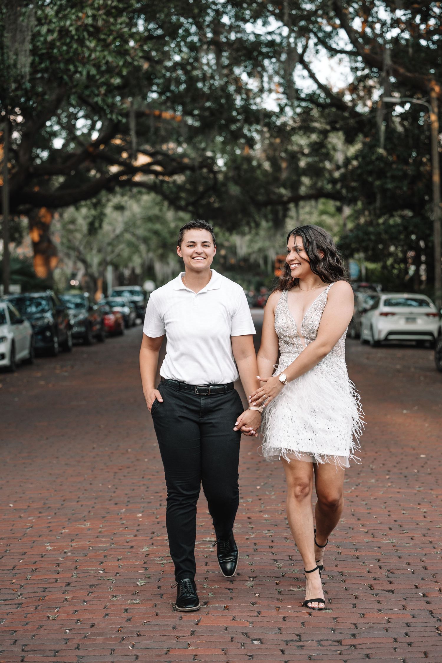 A couple walking together on a brick paved street lined in Savannah.
